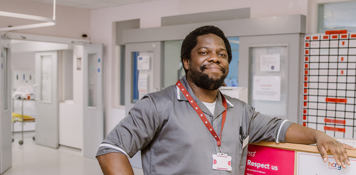 Make nurse smiling and standing by a desk.