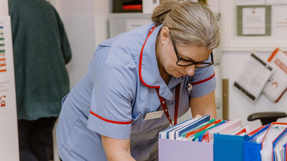 Female nurse looking into a draw of folders.